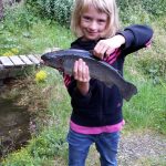 Anna mit der selbst geangelten Forelle bei den Fischteichen auf der Alm