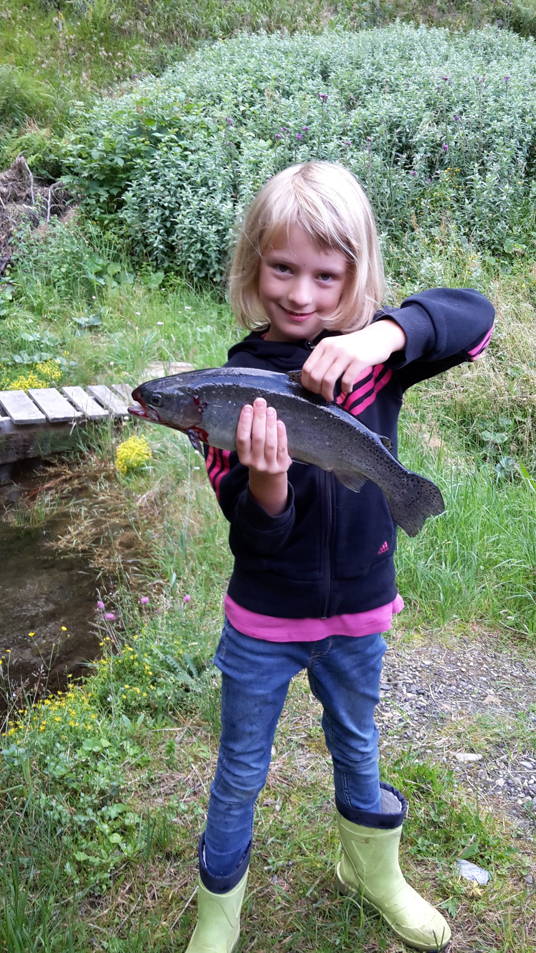 Anna mit der selbst geangelten Forelle bei den Fischteichen auf der Alm